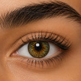 Urban Layer Cleopatra Green coloured contact lens shown on a dark brown eye